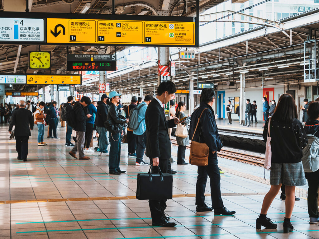 JAPAN, TOKYO - APR 14, 2019 : Business man using mobile phone waiting Train on platform JR Train station Tokyo city Transportation